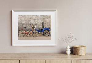 Old red bicycle parked beside blue motorized cart