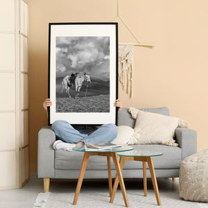 Working horse beneath dramatic cloud formations and mountains