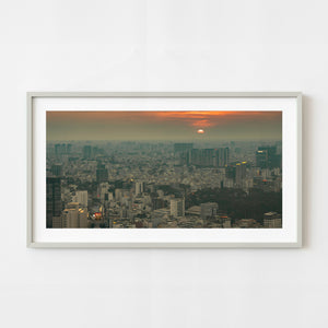 Saigon skyline at sunset beneath orange clouds and atmospheric haze