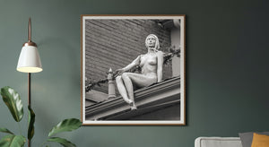 Mannequin sitting on roof edge beside Christmas garland