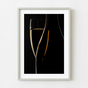 Sparkling wine flute with bubbles beside a dark bottle