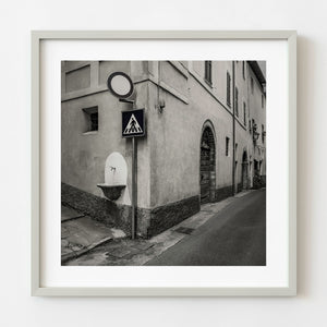 Toned black and white photograph of a wall fountain and traffic signs in Spoleto