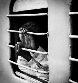 Close view of hands gripping a bar and shielding a face inside an Indian passenger train