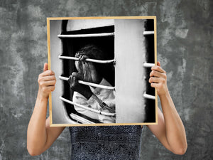 Human hands and a white shirt framed by the bars of an Indian train window