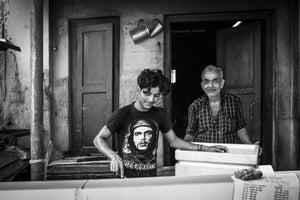 Young and older man inside a weathered Kochi workspace