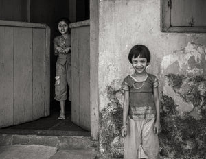 Smiling Indian girl with her sister standing in a doorway