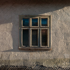 Old six-pane window set in cracked plaster wall