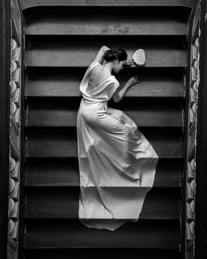 Black and white photograph of woman resting across broad stairs