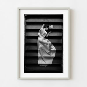 Woman in flowing white gown on dark staircase in Saigon