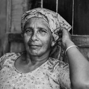 Older Indian woman looking directly forward while resting her hand near her scarf
