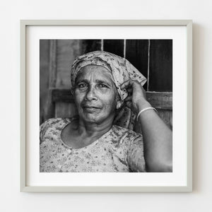 Black and white portrait of an elderly woman seated inside a shop in India
