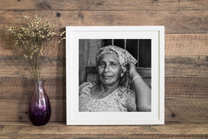Monochrome environmental portrait of an older woman inside a small shop