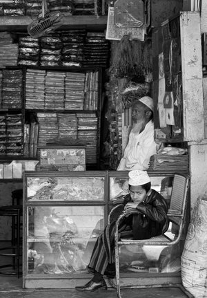 Black and white portrait of a boy leaning on a shop chair in India