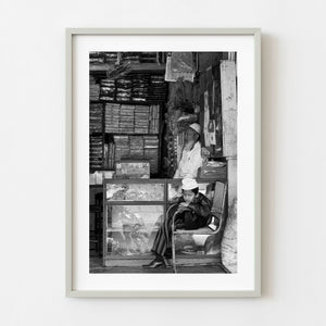Young boy seated inside an Indian shop in black and white