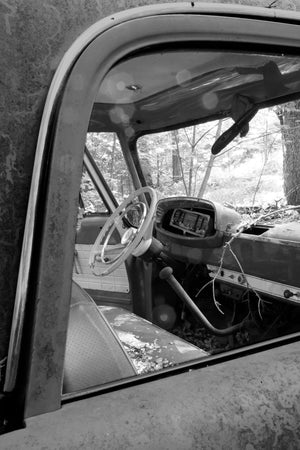 Black and white photograph through the open side of an abandoned Dodge truck cab.
