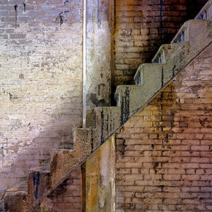 Colour photograph of stone steps and worn brickwork inside an abandoned factory.
