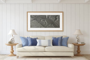 A sweeping channel crosses textured grey coastal land in an abstract aerial landscape.