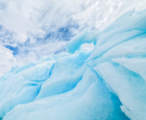 Folds and blue recesses of Antarctic ice with bright sky visible through an opening.