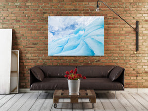 Pale iceberg ridges and shaded blue grooves rising toward white clouds.
