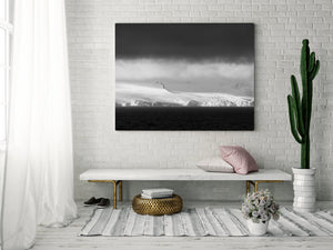 Blowing snow softens Antarctic ice cliffs beneath a subdued blue-grey sky.