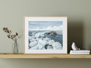 Rounded Antarctic coastal rocks surrounded by pale blue and white ice.