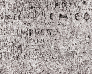Close monochrome photograph of inscriptions scratched into Blarney Castle stone.