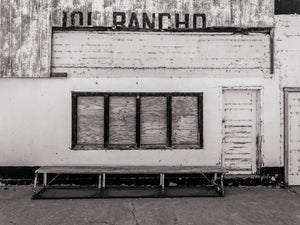 Faded restaurant sign above boarded windows and a bench in Zion
