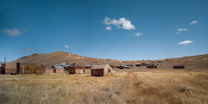 Weathered wooden buildings in Bodie, California, surrounded by dry grass