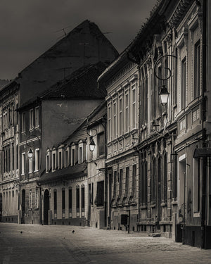 Tall windows and ornate facades line an empty Brasov street in early light
