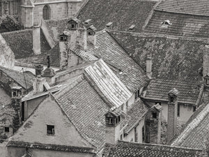 Old clay tiles form overlapping slopes among Bucharest chimneys and roof windows.