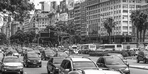 Cars and buses fill a broad Buenos Aires avenue below rows of city buildings.
