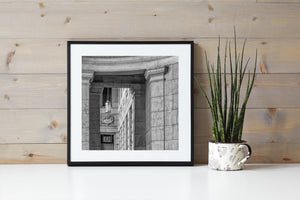 Repeated windows and carved masonry seen between heavy classical columns.
