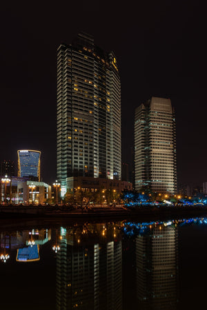 Illuminated high-rise buildings rise against a black sky beside the Chengdu waterfront.