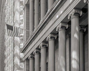 Fluted stone columns recede along a New York facade beside an American flag and distant windows.