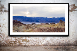 Layered Death Valley terrain forms soft folds of muted colour under overcast light.