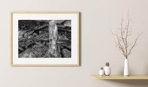 Monochrome cave interior showing layered rock surfaces and a central natural column.