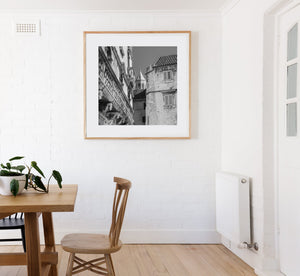 Historic Croatian architecture surrounds a narrow opening with a bell tower beyond.