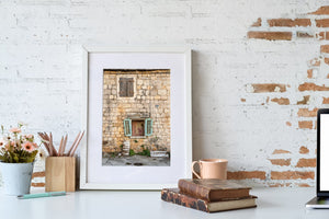 Worn masonry, faded shutters and small plants surround the windows of a Croatian home.