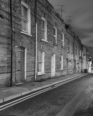 Repeating doors and pale window frames along a quiet Derry street, monochrome photograph.