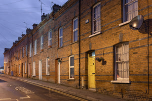 Yellow door and repeating brick homes along a Derry street at dusk.