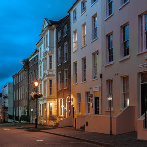Tall Derry facades receding beside an empty street at dusk, colour photograph.