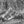 Rounded desert rock formations beneath a fractured cliff wall, monochrome photograph.