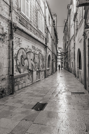 Black and white Dubrovnik alley between tall stone buildings