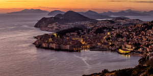 Panoramic Dubrovnik sunset with coastal buildings, islands and glowing harbour lights