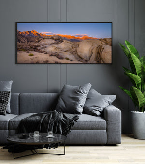 Golden morning light on rugged Sierra mountains beyond weathered desert boulders