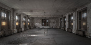 Panoramic colour photograph of an empty Ellis Island hospital ward with a chair near the centre.