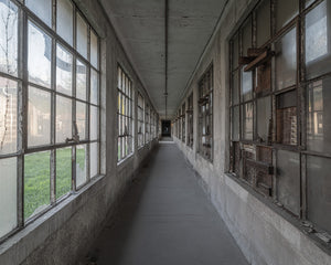 Colour architectural photograph of a long abandoned hospital hallway on Ellis Island.