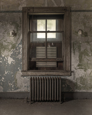 Muted colour photograph of a window and radiator against peeling hospital walls.