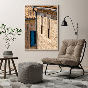 Sunlight highlights rough stonework and narrow windows on a traditional French house