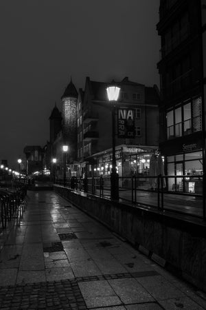 Reflections shine on stone paving beside restaurants along Gdańsk’s waterfront